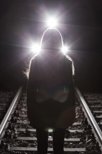 Girl standing on rails and the train in background
